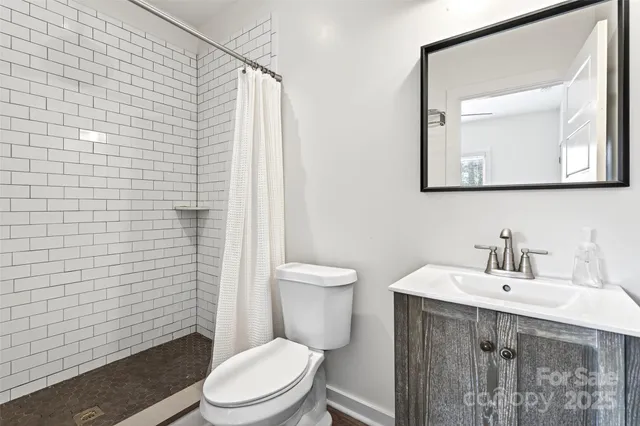 a bathroom with a toilet a sink a mirror and a shower