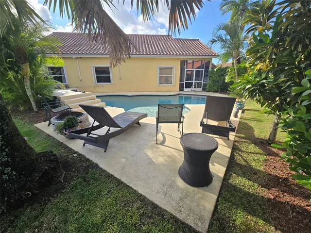 a view of a patio with table and chairs potted plants and a large tree