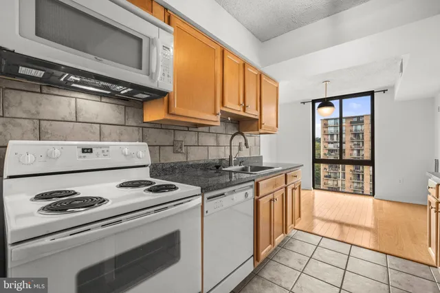 a kitchen with granite countertop a stove sink and cabinets