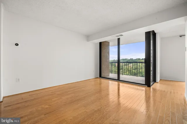 a view of an empty room with wooden floor and a floor to ceiling window