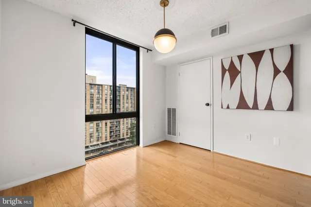 a view of an empty room with window and wooden floor