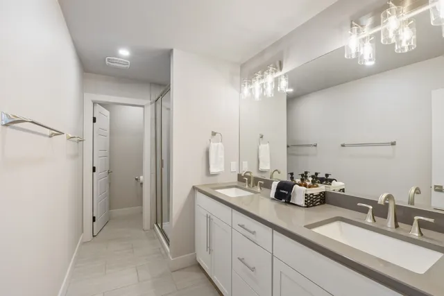 a bathroom with double vanity sinks a vanity a mirror and shower
