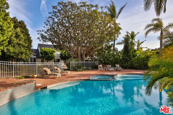 a view of a swimming pool with a bench and trees