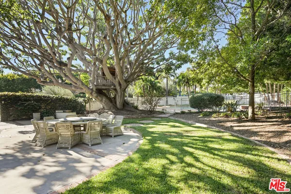 a view of a patio with table and chairs and couches with large trees