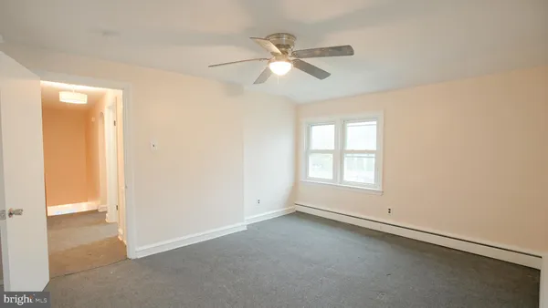 an empty room with a window and a fan