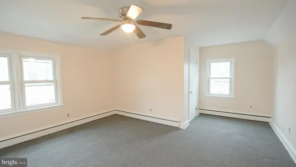 an empty room with a window and a fan