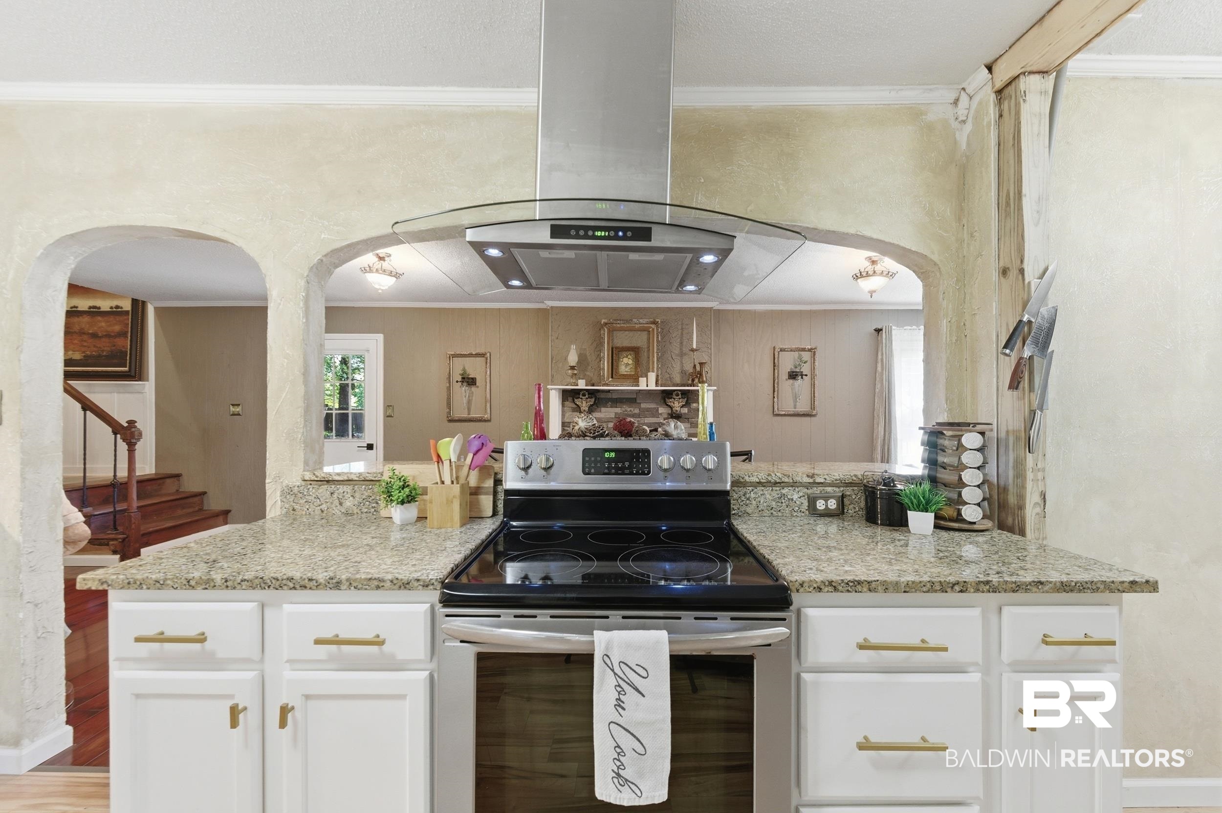 51620 Robert White Road Bay Minette, AL 36507 - Photo 33 of 81 Kitchen featuring a stainless steel range with a glass cooktop, a stainless steel and glass range hood, white cabinetry with gold-tone hardware, and light-toned speckled countertops