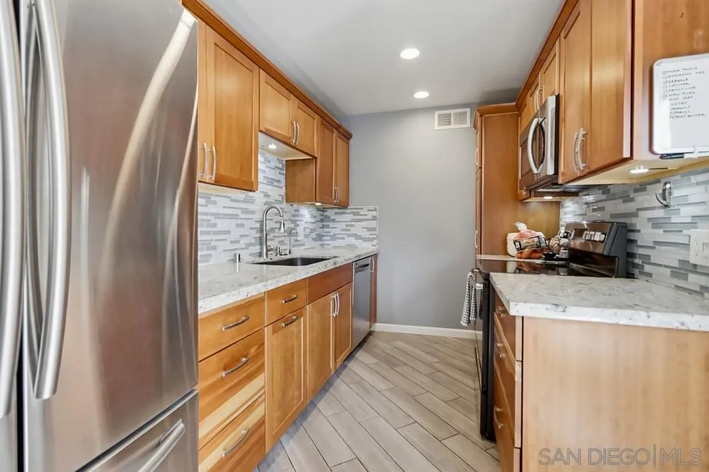 6416 Friars Road, Unit 111 San Diego, CA 92108 - Photo 4 of 21 a kitchen with stainless steel appliances granite countertop a refrigerator a sink dishwasher a stove and white countertops with wooden floor