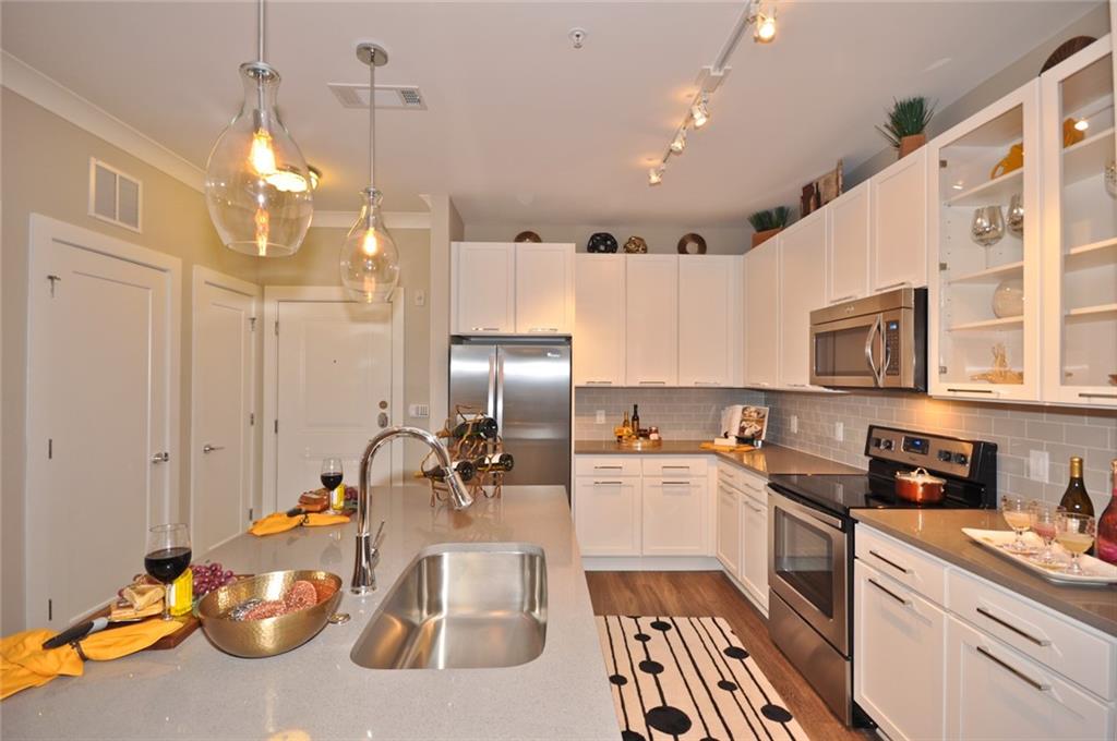 2875 Crescent Parkway, Unit 1117 Smyrna, GA 30080 - Photo 2 of 23 a kitchen with a sink dishwasher a stove and a refrigerator with wooden floor