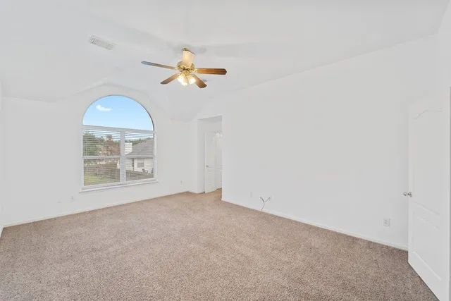 an empty room with a window and a ceiling fan