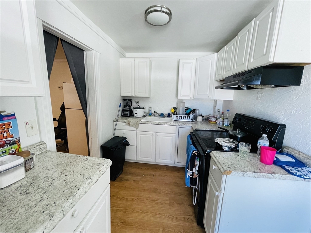 92 Mill Street Lancaster, MA 01523 - Photo 11 of 26 a kitchen with a sink dishwasher stove and white countertops with wooden floor