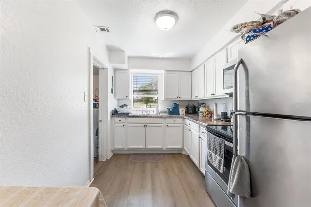 a kitchen with a sink a refrigerator and cabinets
