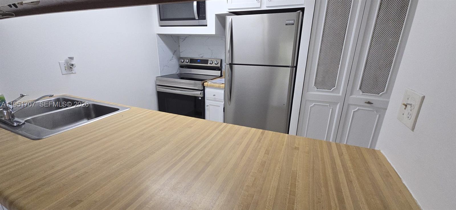 3680 Inverrary Drive, Unit 3M Lauderhill, FL 33319 - Photo 14 of 60 a bedroom with a bed and a refrigerator