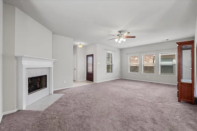 a view of an empty room with chandelier fan and a fireplace