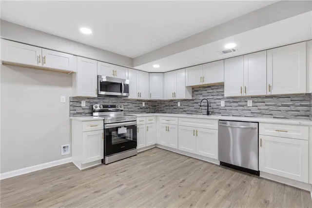 a kitchen with granite countertop white cabinets and stainless steel appliances