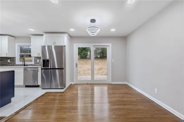 a view of a kitchen with a sink refrigerator and wooden floor