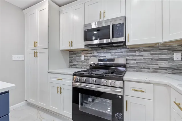a kitchen with granite countertop a stove top oven microwave and cabinets
