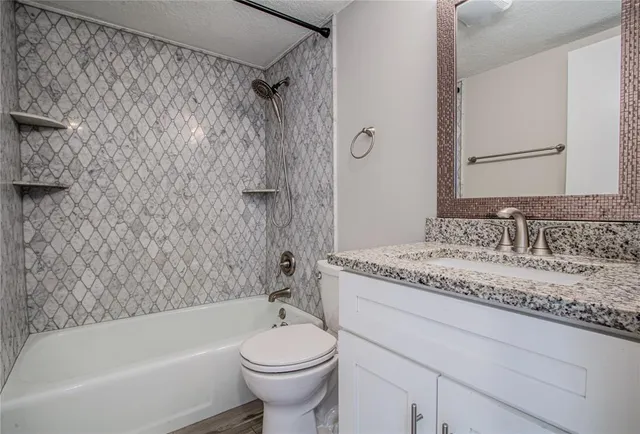a bathroom with a granite countertop sink toilet and bathtub