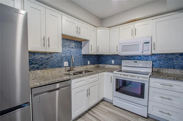 a kitchen with stainless steel appliances granite countertop a sink stove and cabinets
