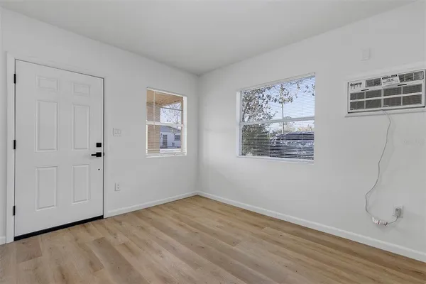 a view of an empty room with wooden floor and a window