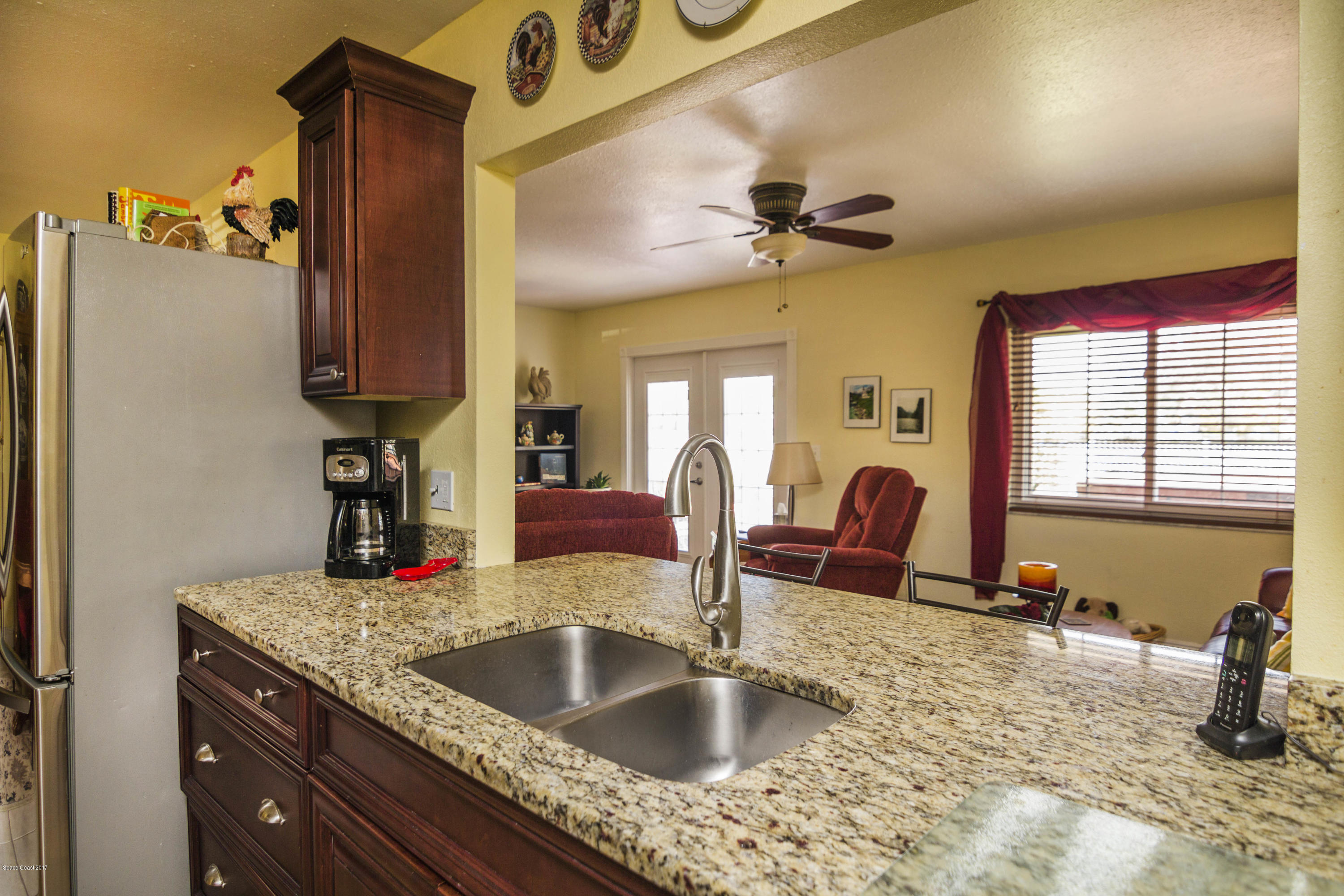 905 Riviera Drive Northeast Palm Bay, FL 32905 - Photo 7 of 21 a kitchen with a granite countertop sink a refrigerator and chandelier