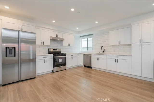 a large kitchen with a refrigerator sink and cabinets
