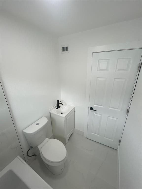 1457 West 31st Street, Unit 2 Riviera Beach, FL 33404 - Photo 13 of 16 a white toilet sitting next to a bathroom sink