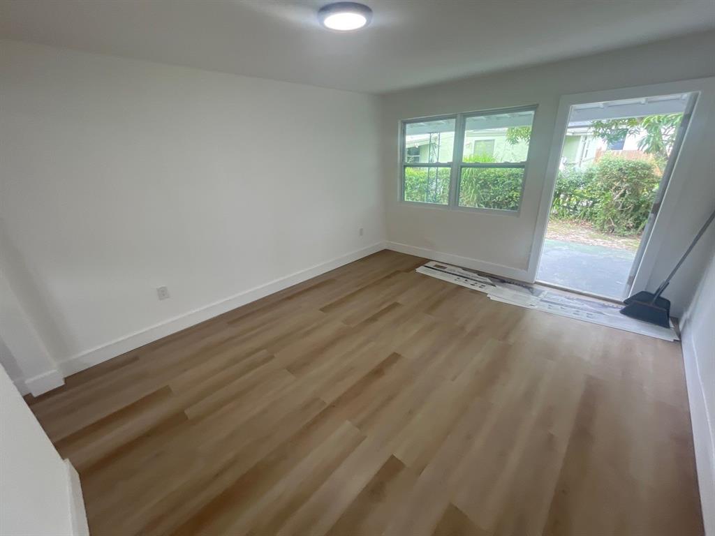 1457 West 31st Street, Unit 2 Riviera Beach, FL 33404 - Photo 4 of 16 an empty room with wooden floor and windows
