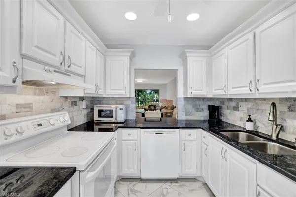 a kitchen with white cabinets and white appliances