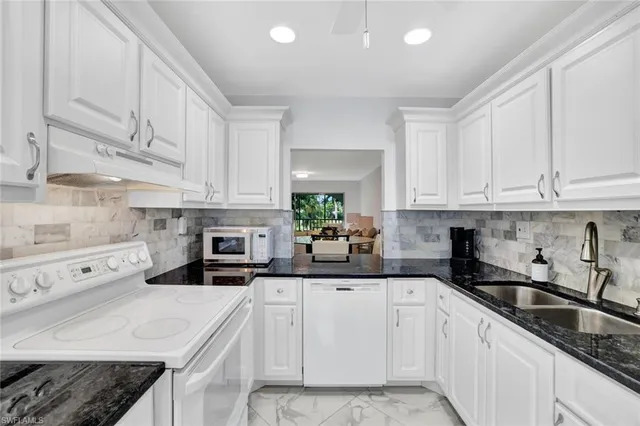 a kitchen with white cabinets and white appliances
