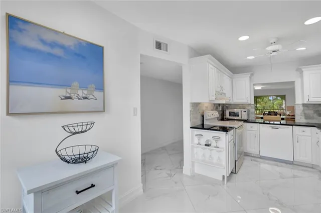 a kitchen with white cabinets and appliances