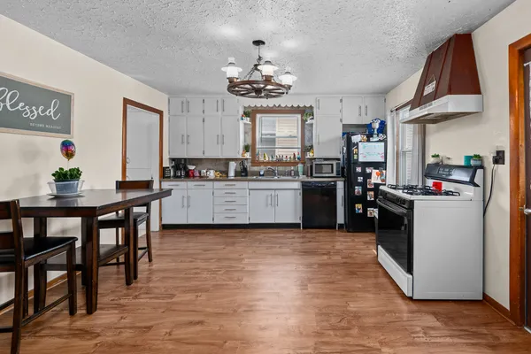 a kitchen with stainless steel appliances kitchen island granite countertop a stove top oven a sink a dining table and chairs