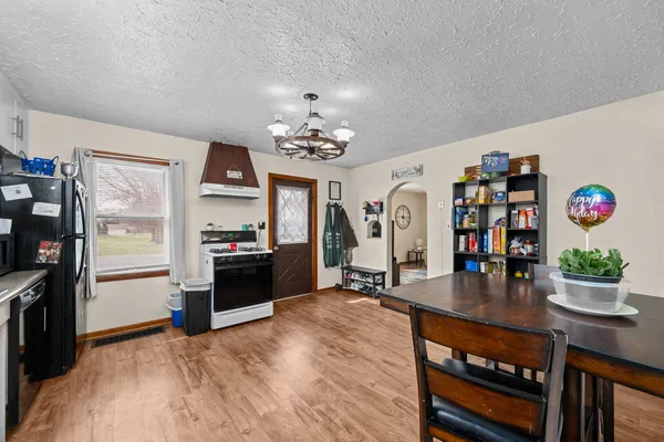 a living room with stainless steel appliances furniture a chandelier and a kitchen view