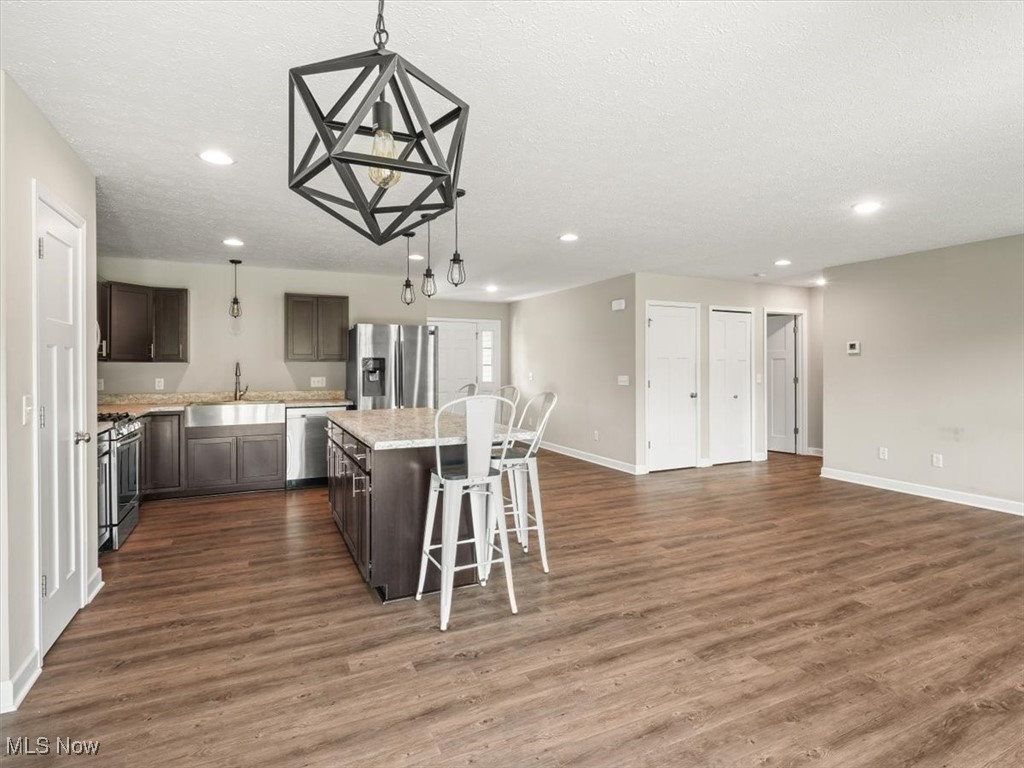 5525 White Road Geneva, OH 44041 - Photo 14 of 28 Kitchen with wood-type flooring, hanging light fixtures, sink, a kitchen island, and appliances with stainless steel finishes