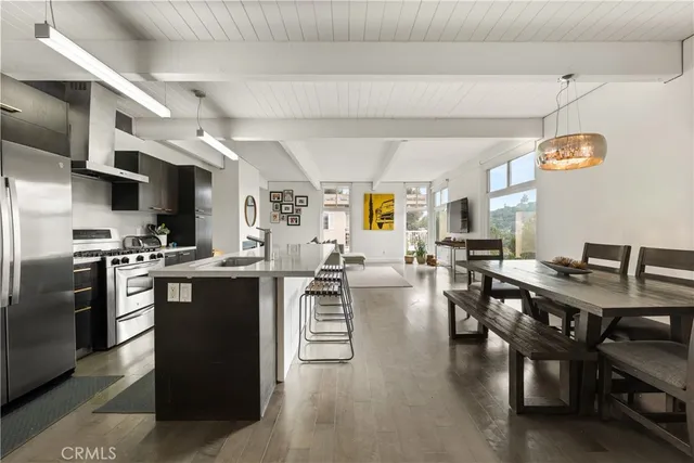 a kitchen with stainless steel appliances kitchen island granite countertop a table chairs and a refrigerator