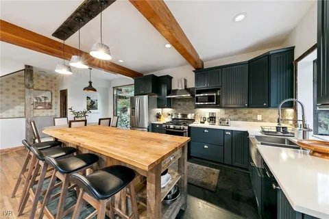 a kitchen with stainless steel appliances granite countertop a sink a stove and chairs