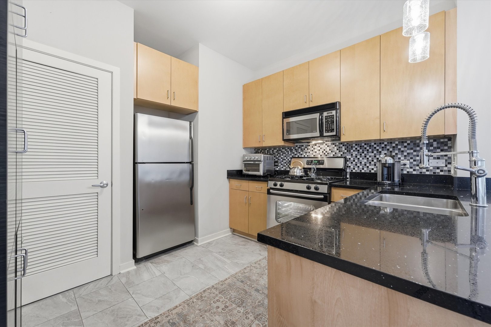 1155 West Roosevelt Road, Unit 404 Chicago, IL 60608 - Photo 7 of 30 a kitchen with granite countertop a refrigerator and a sink