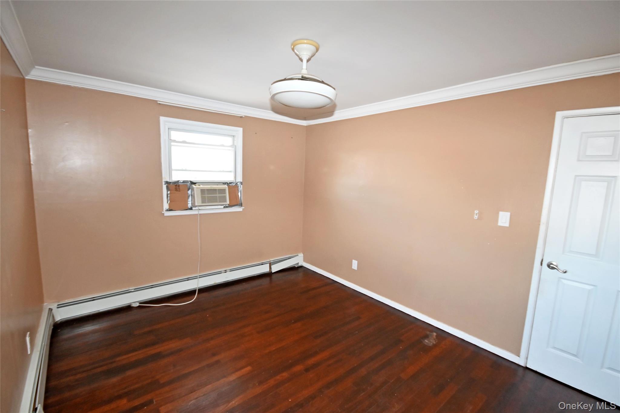 89 Osborne Road West Hempstead, NY 11552 - Photo 11 of 50 Empty room featuring crown molding, dark wood-style floors, baseboard heating, and cooling unit