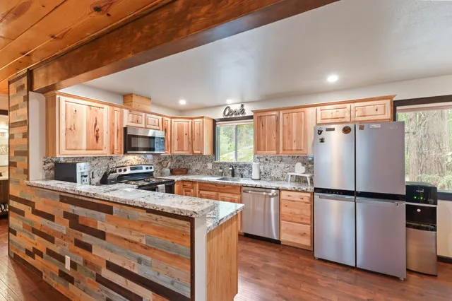 a kitchen with stainless steel appliances granite countertop a refrigerator a stove a sink and a microwave