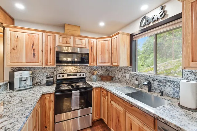 a kitchen with granite countertop a sink stainless steel appliances and cabinets