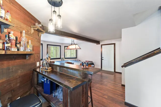 a view of a kitchen with granite countertop a sink dishwasher a stove and a dining table with wooden floor