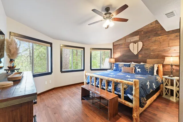 a bedroom with a bed and a large window with wooden floor