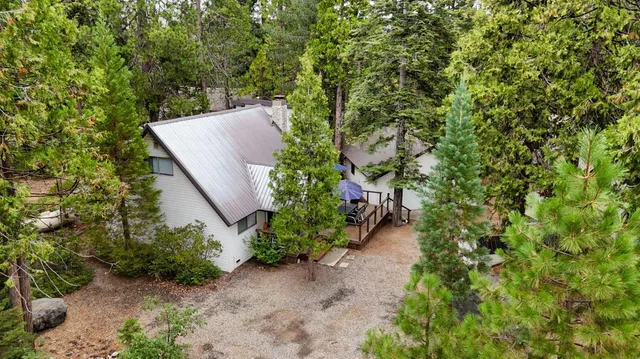 an aerial view of a house with a yard and trees all around