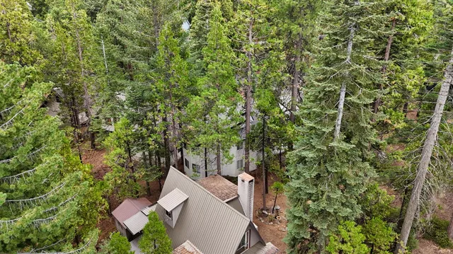 an aerial view of residential house with outdoor space and trees all around