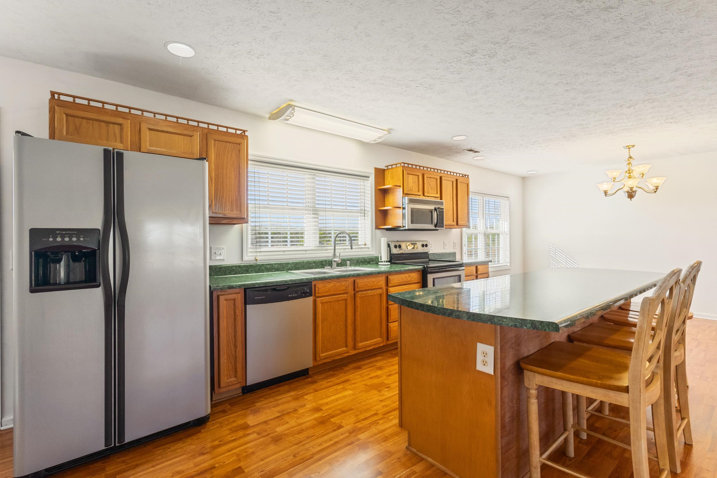 3923 State Rd S-26-33 Green Sea, SC 29545 - Photo 18 of 40 Kitchen featuring stainless steel appliances, brown cabinetry, a kitchen island, a breakfast bar area, and light wood-type flooring