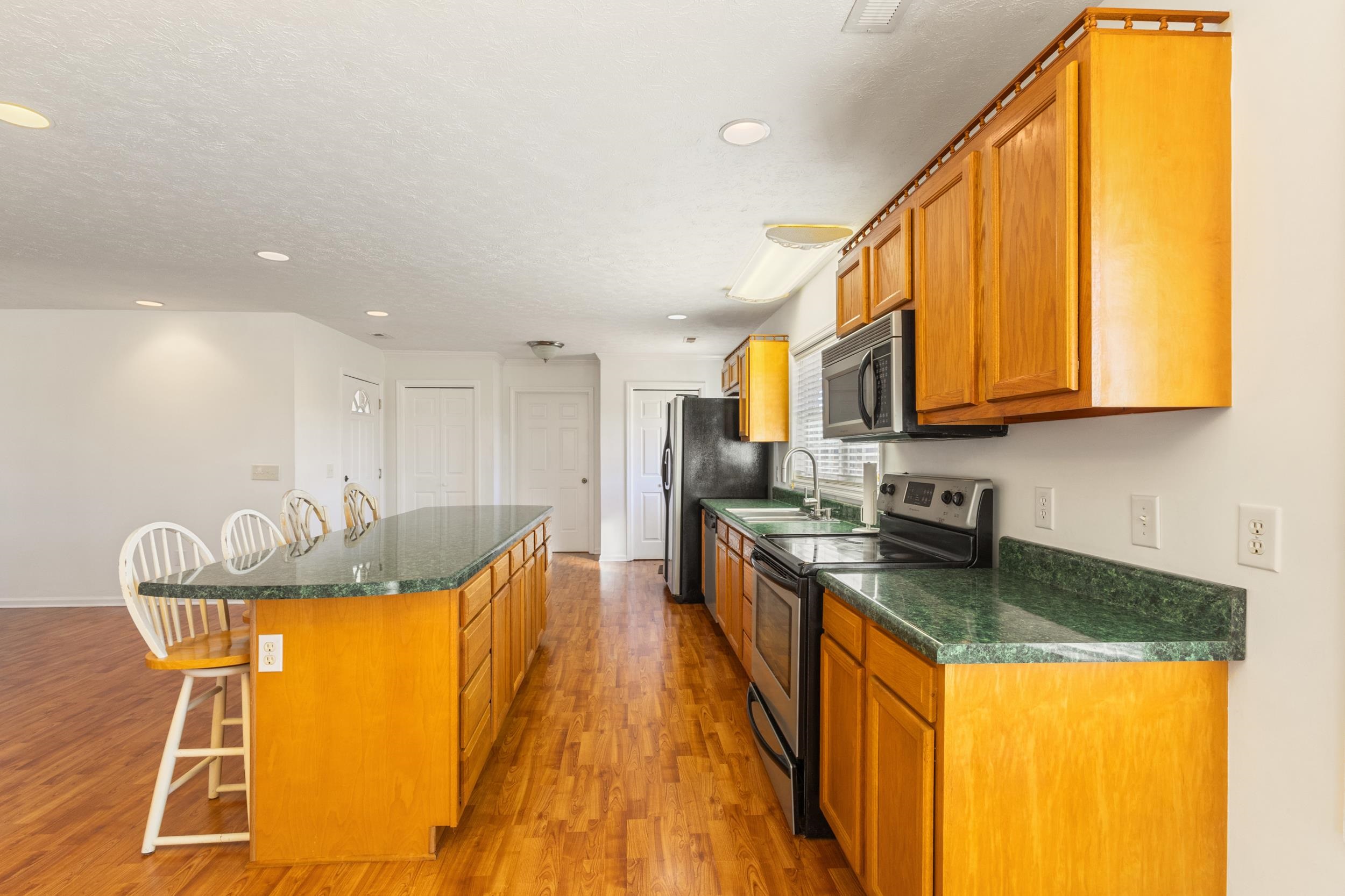 3923 State Rd S-26-33 Green Sea, SC 29545 - Photo 20 of 40 Kitchen with a breakfast bar, stainless steel appliances, a center island, brown cabinets, and light wood-style flooring