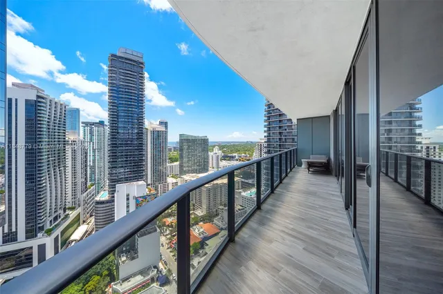 a view of balcony with a couple of cars parked in front of buildings