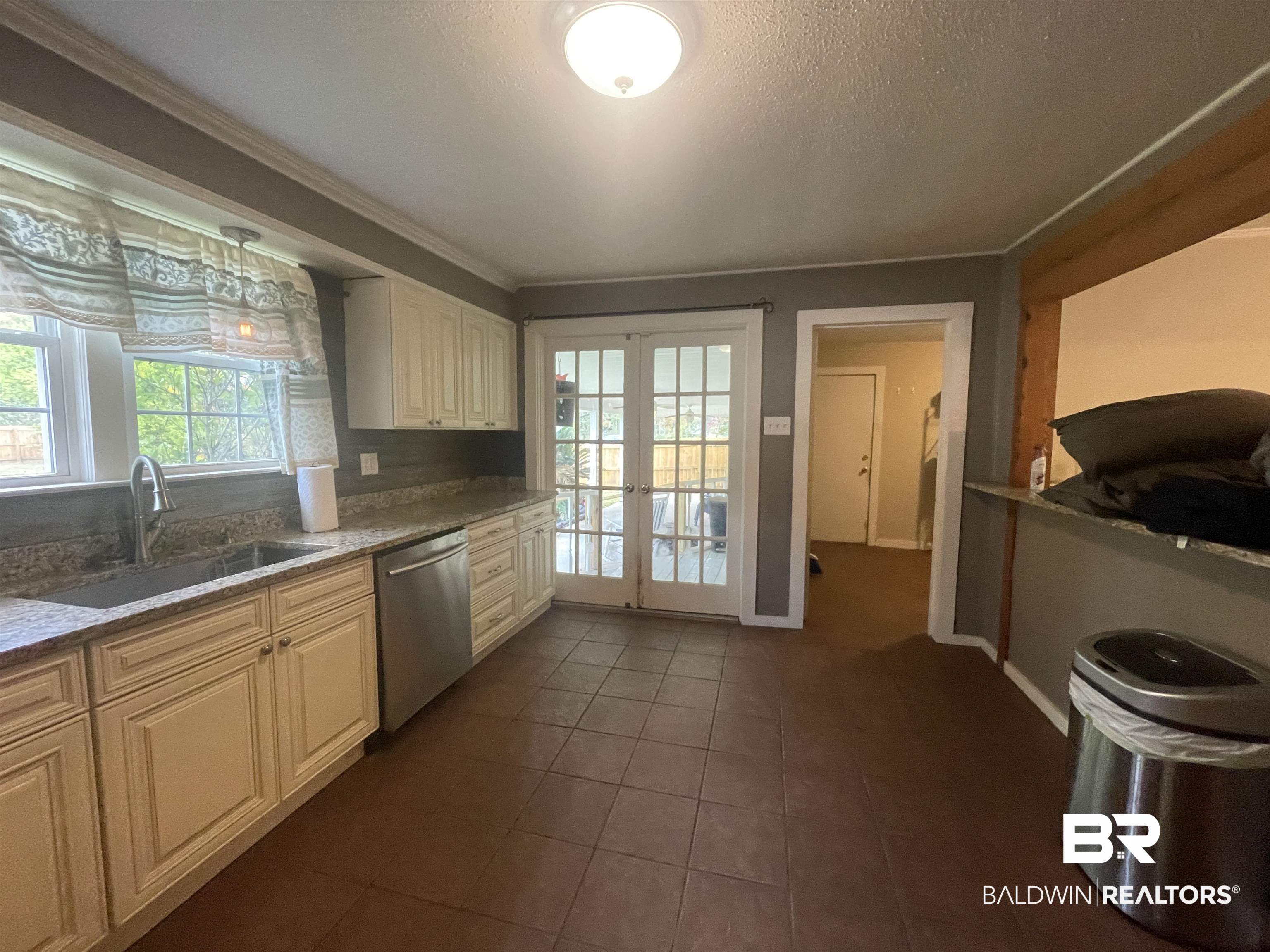 13850 Celeste Road Chunchula, AL 36521 - Photo 11 of 29 Kitchen featuring healthy amount of natural light, stainless steel dishwasher, light stone countertops, dark tile patterned flooring, and a textured ceiling