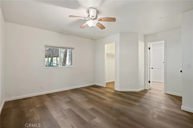 an empty room with wooden floor and ceiling fan