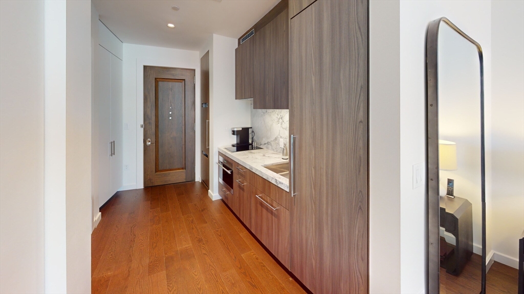 40 Trinity Place, Unit 1503 Boston, MA 02116 - Photo 7 of 14 a hallway with stainless steel appliances granite countertop a sink and a refrigerator